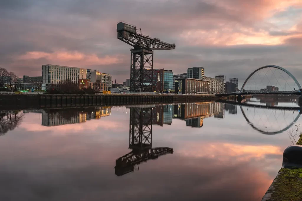 Scenic view of Glasgow's River Clyde at sunset, featuring the iconic Finnieston Crane, modern city buildings, and the Clyde Arc bridge reflected in the calm water, relevant to the search for Mechanical Fitter jobs Glasgow.